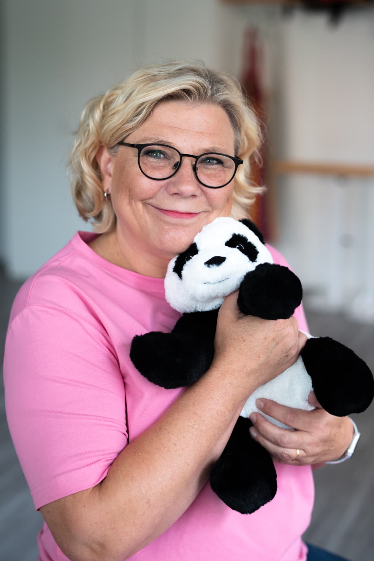 Fysioterapeut Eva Teijonsalo ler och håller ett mjukt pandagosedjur i famnen
